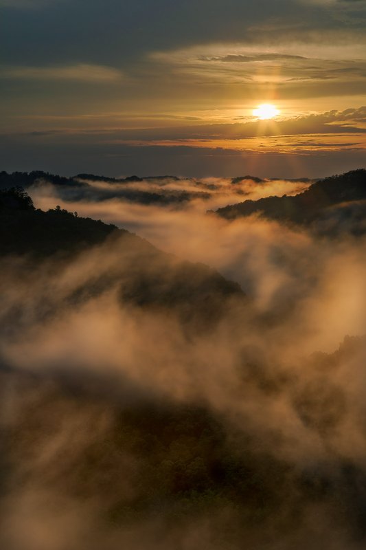 Fog rolls through the valley as the sun descends