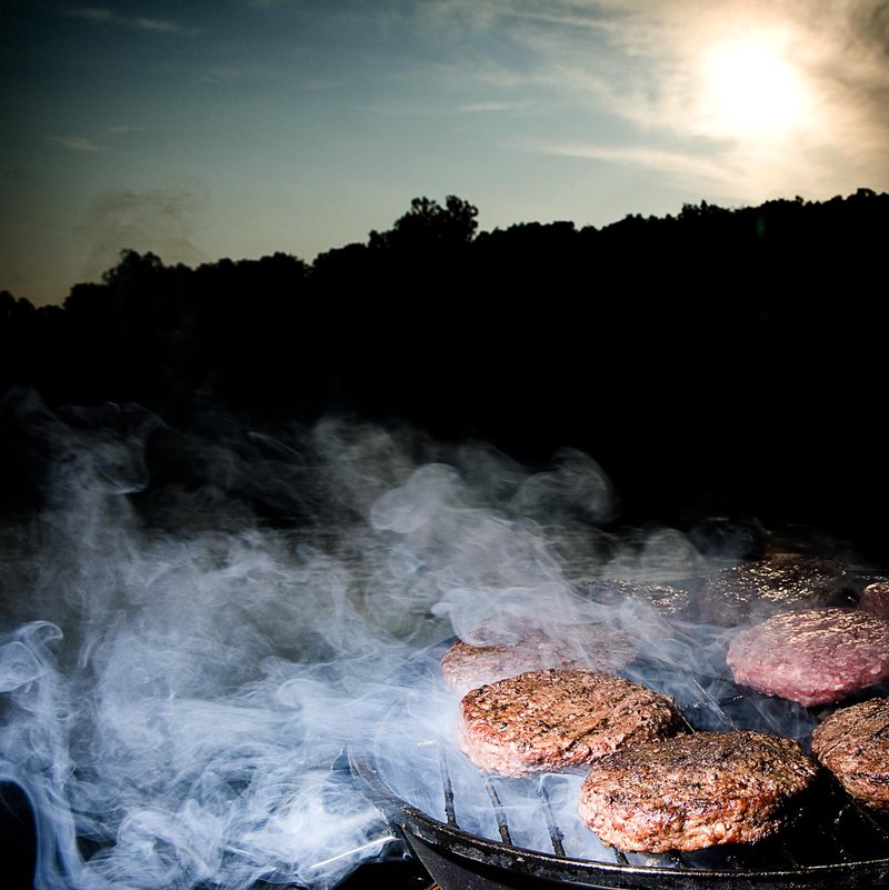 Burgers cooking on a grill during sunset over a Labor Day Weekend